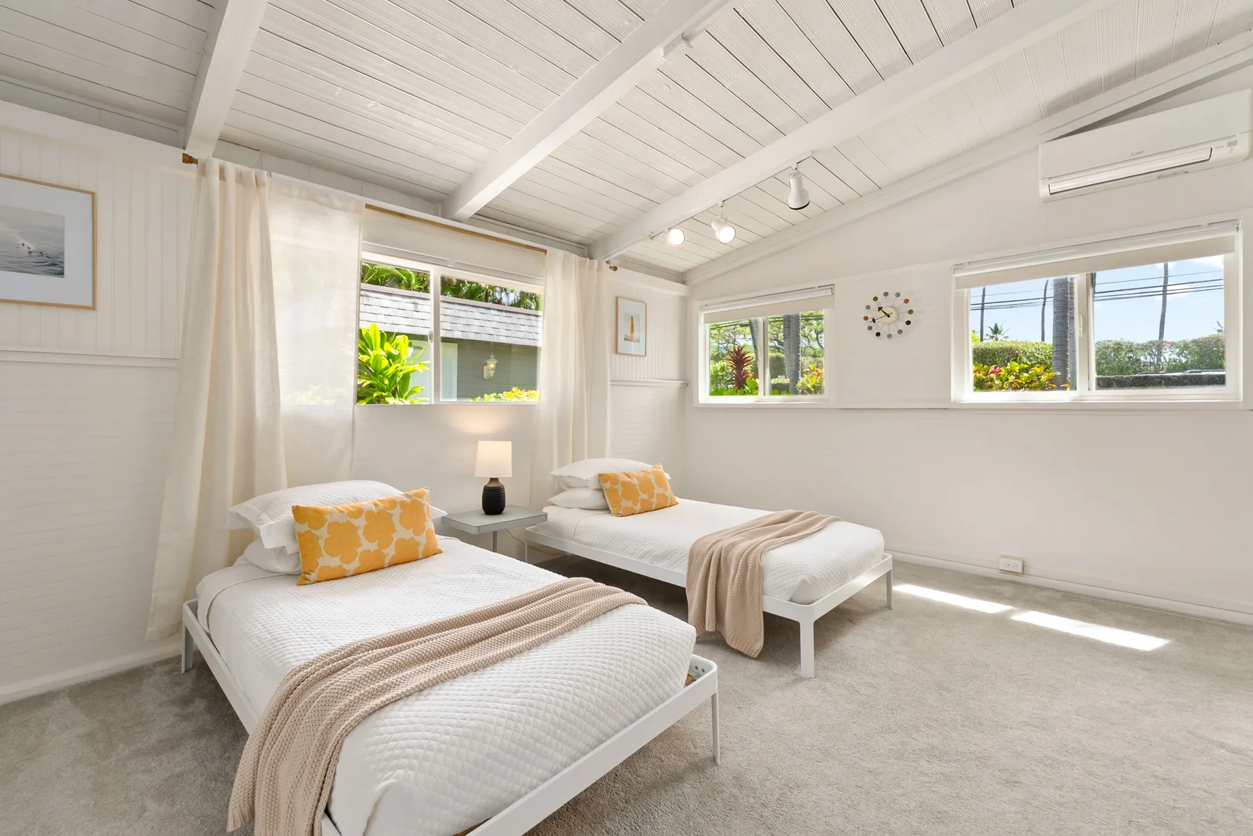 Un dormitorio luminoso con dos camas y ventanas amplias.