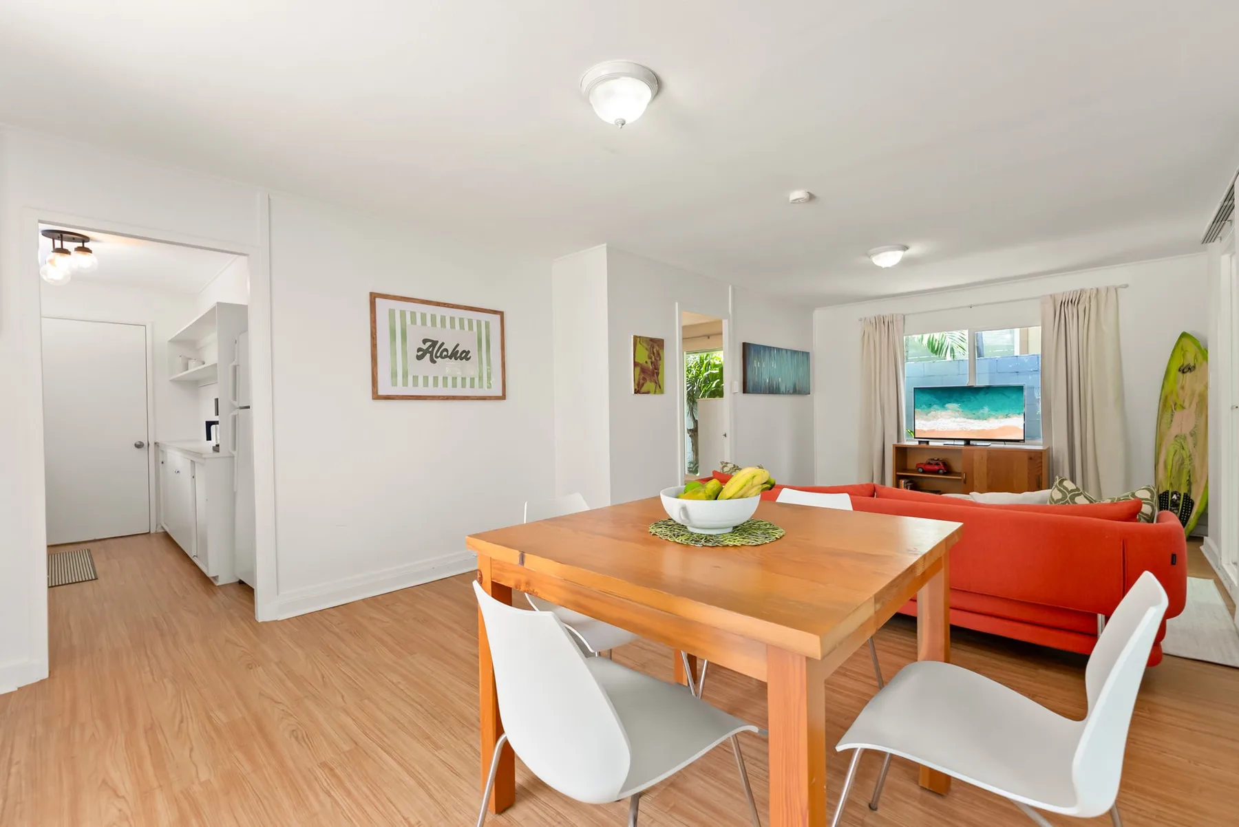 Un comedor y sala luminosos con una mesa de madera y asientos rojos.