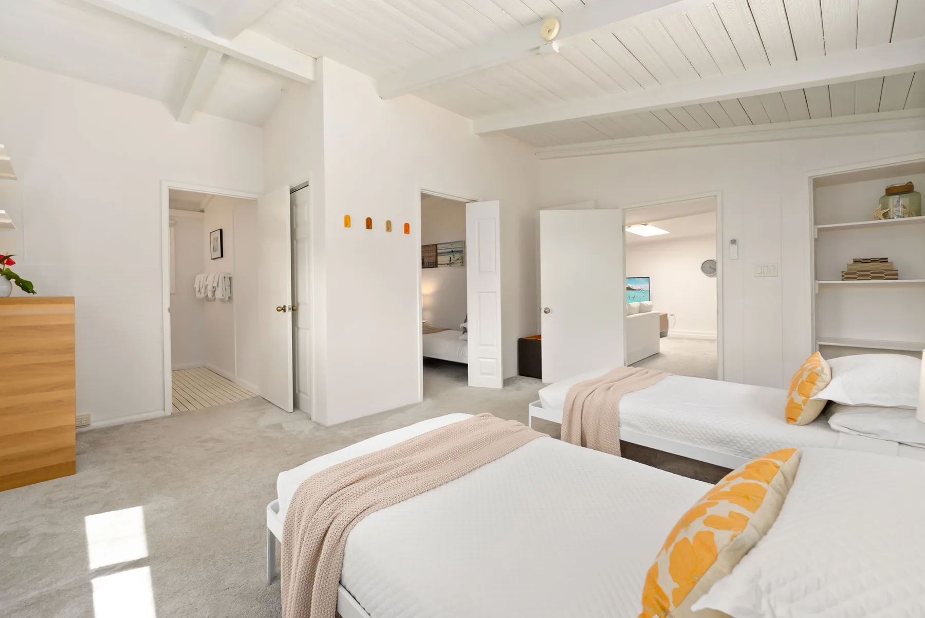 Un dormitorio luminoso con dos camas y ropa de cama blanca.