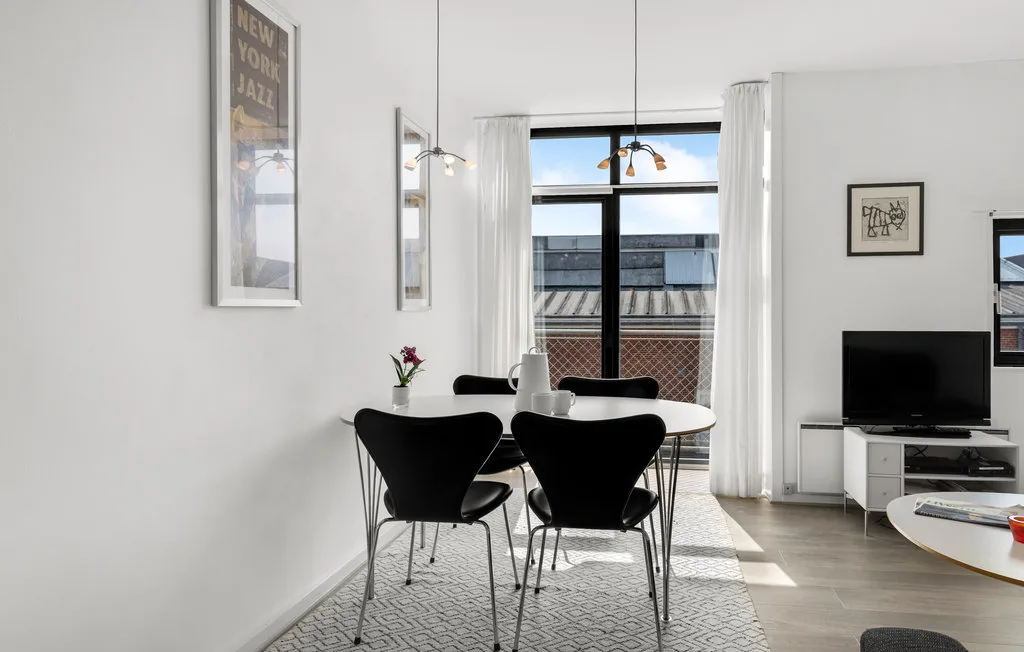 Un comedor luminoso con una mesa y asientos junto a una ventana grande.
