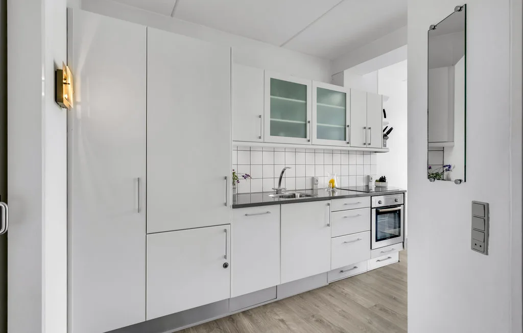 Una cocina blanca y luminosa con gabinetes, una encimera y un horno integrado.