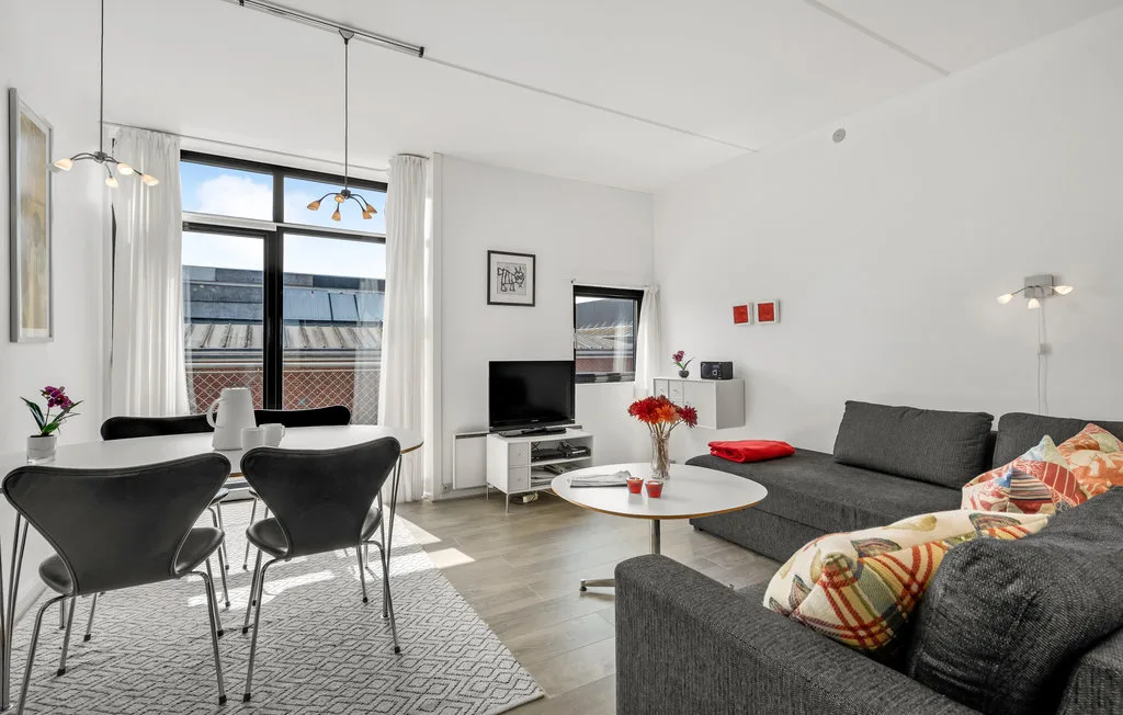 Una sala luminosa con mesa de comedor y asientos junto a grandes ventanas.