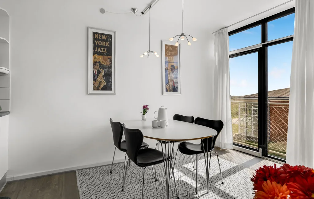 Comedor con una mesa redonda y asientos negros junto a una ventana amplia.