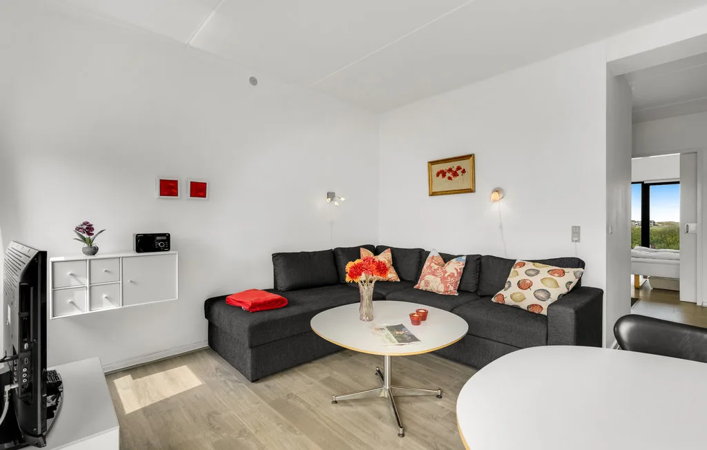 Una sala luminosa con un sofá seccional oscuro y una mesa de centro redonda.