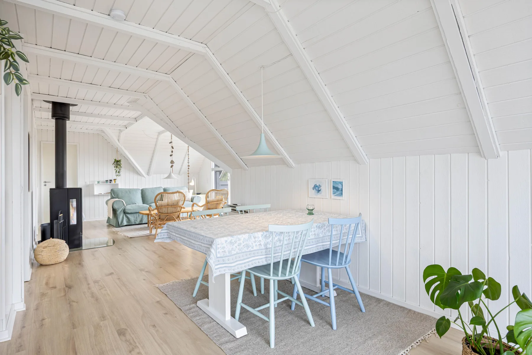 A bright dining area with a table and seating beneath a sloped white ceiling.