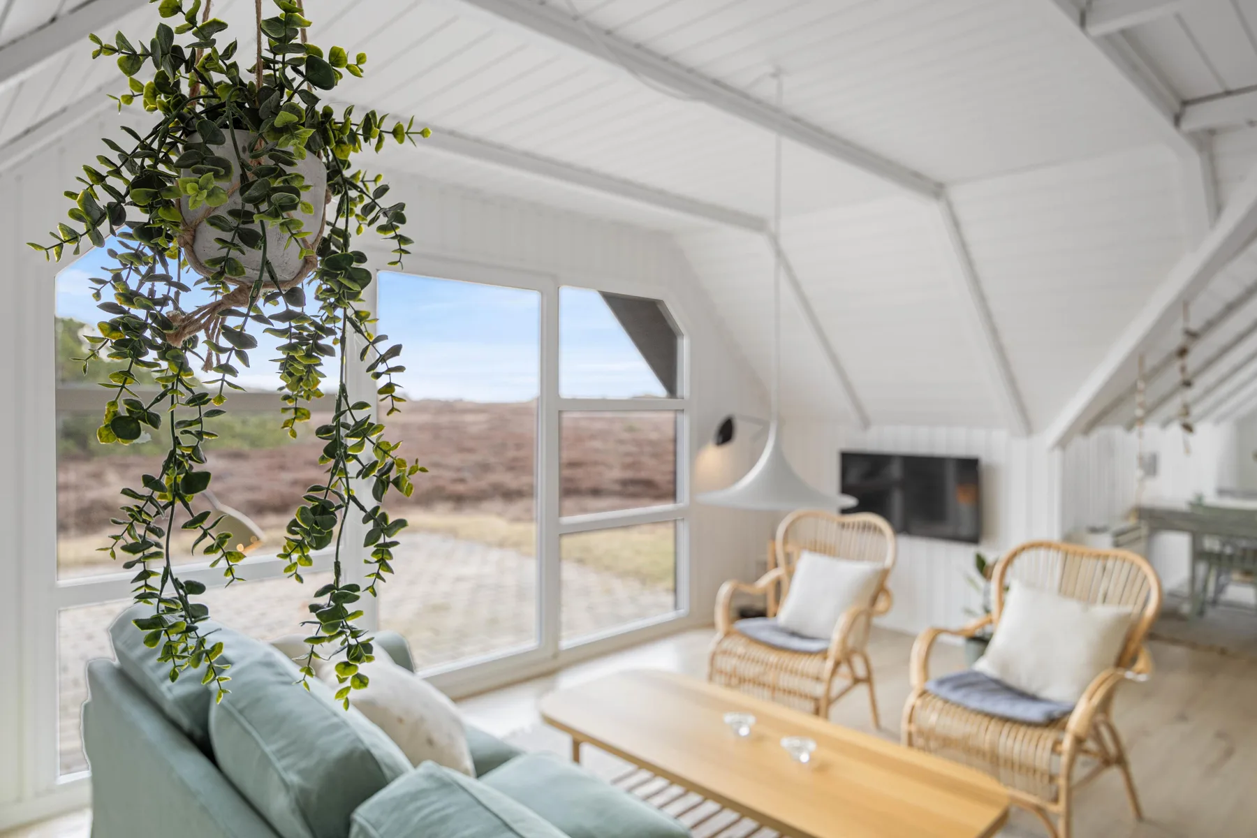 A bright living room with seating beside large windows overlooking the landscape.
