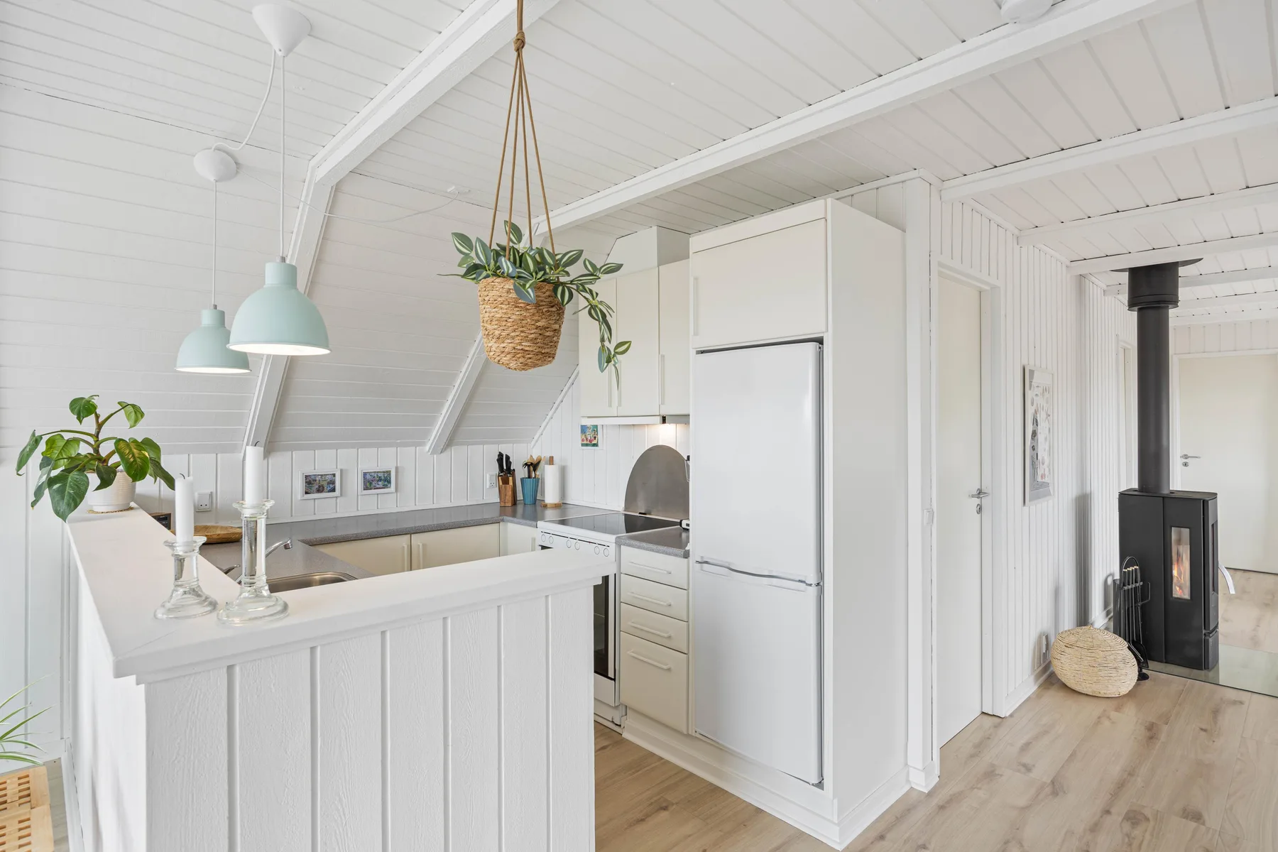 A bright kitchen with a central counter and a wood-burning stove nearby.