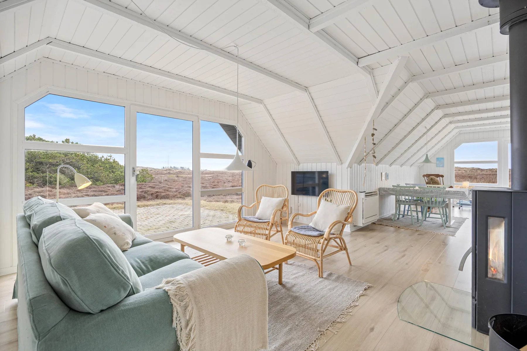 A bright living room with seating, large windows, and a wood-burning stove.