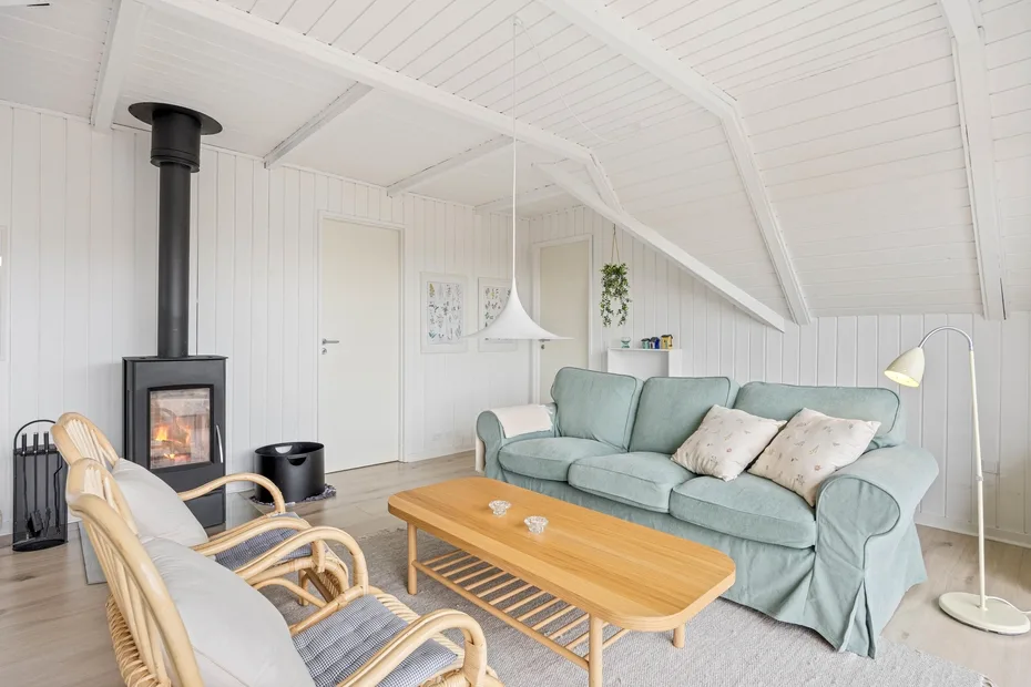 A bright attic living room with a pale sofa and wood-burning stove.