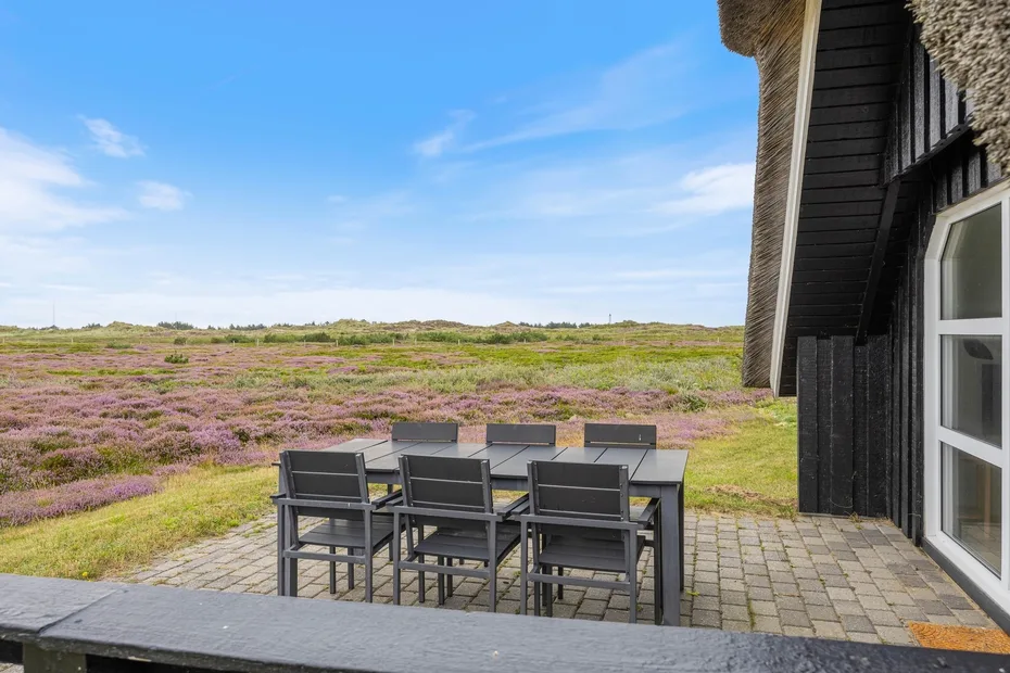 An outdoor patio with seating overlooks a broad field of purple flowers.