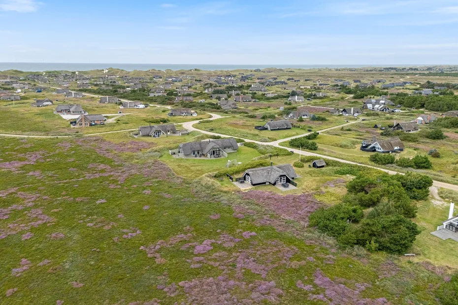 An aerial view shows scattered houses among open green fields and winding roads.