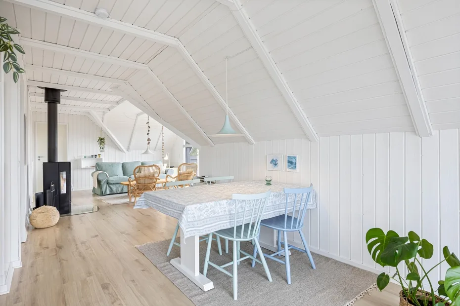 A bright attic dining area with a table and seating beneath a sloped ceiling.