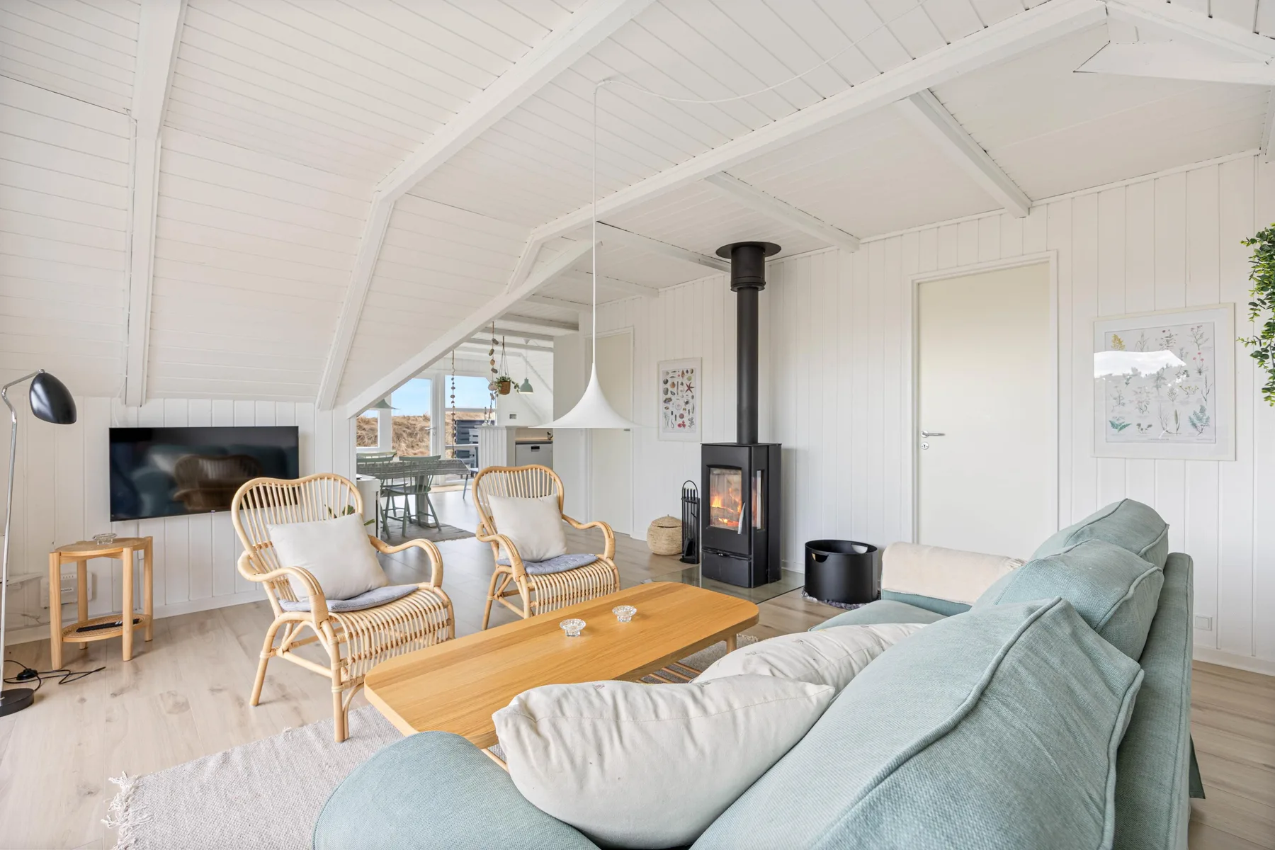 A bright living room with seating, a coffee table, and a wood-burning stove.