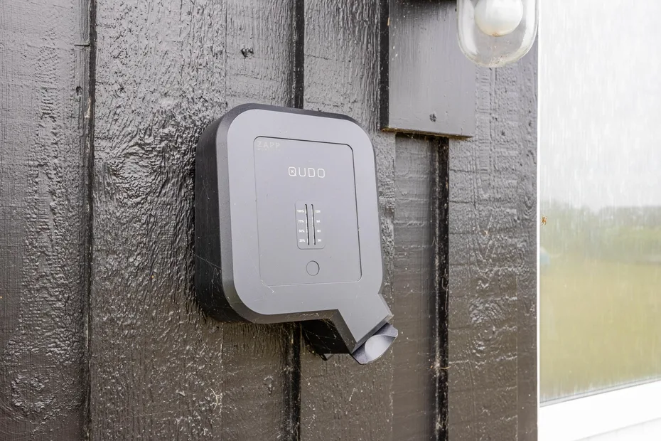 A keypad is mounted on a dark exterior wall beside a window.