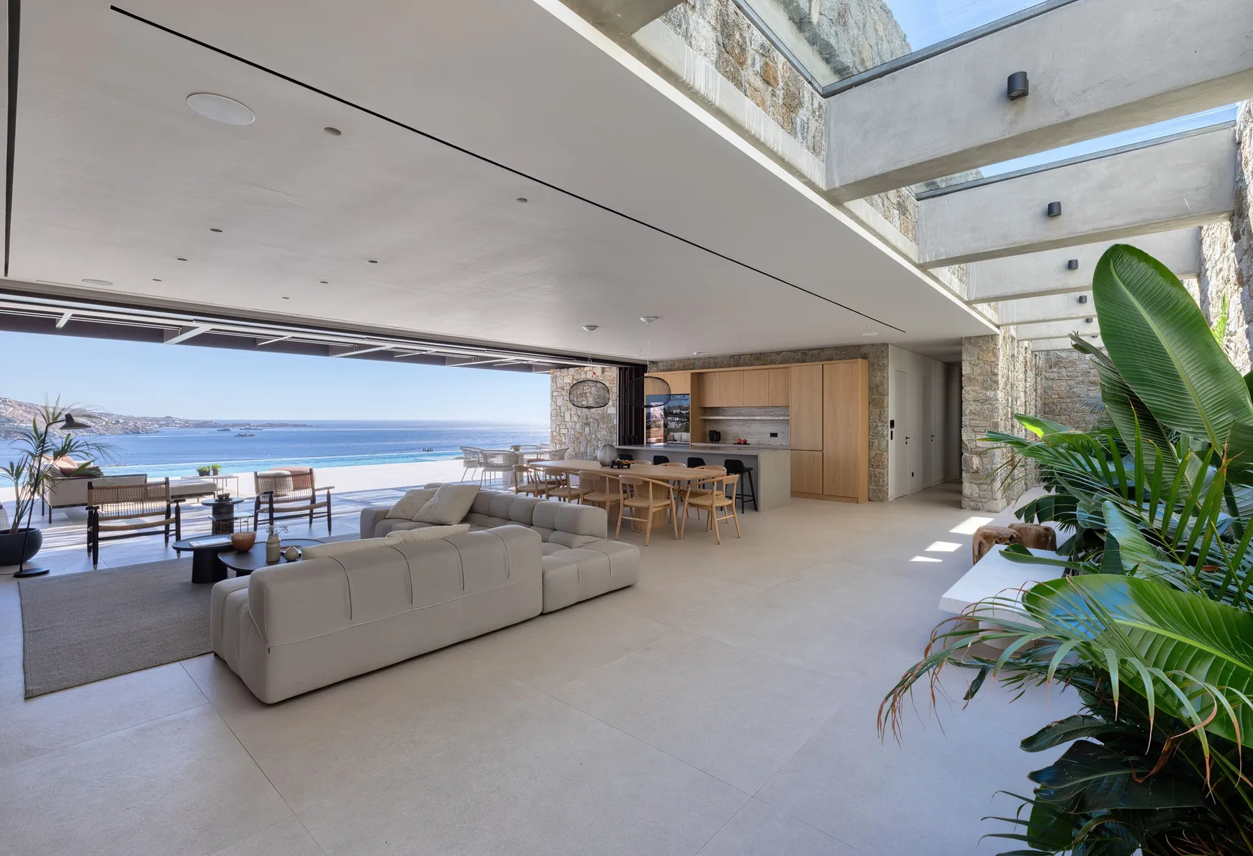 An open living and dining area faces the sea, with seating and a kitchen.