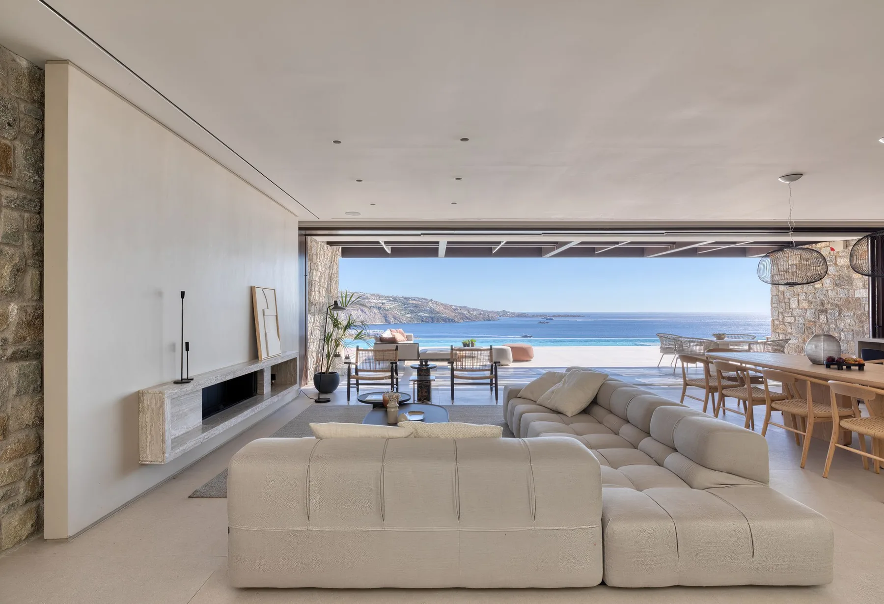 Una sala luminosa con asientos y comedor abierto hacia el mar.
