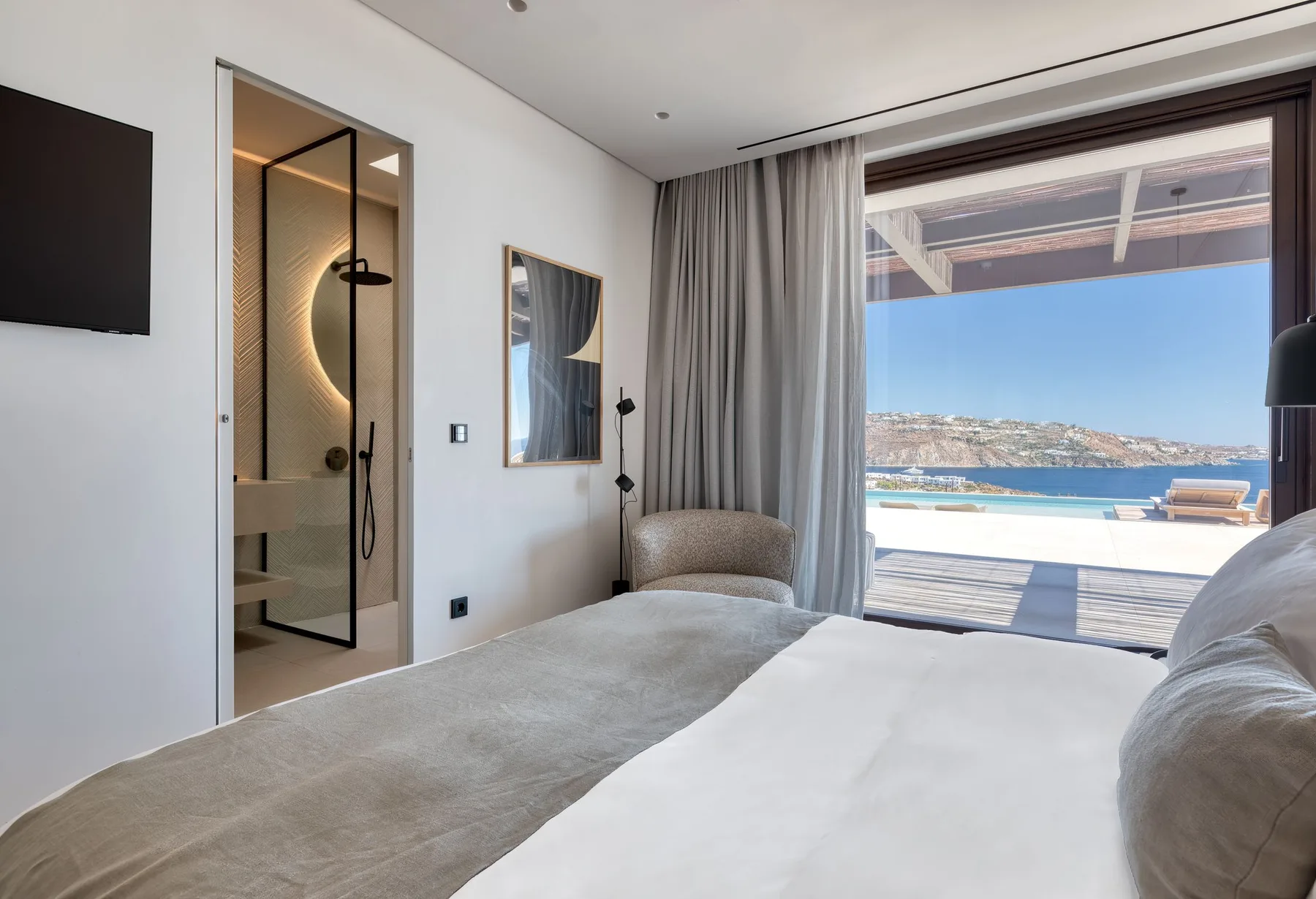 Un dormitorio con una cama, una ducha de cristal y vistas al mar.