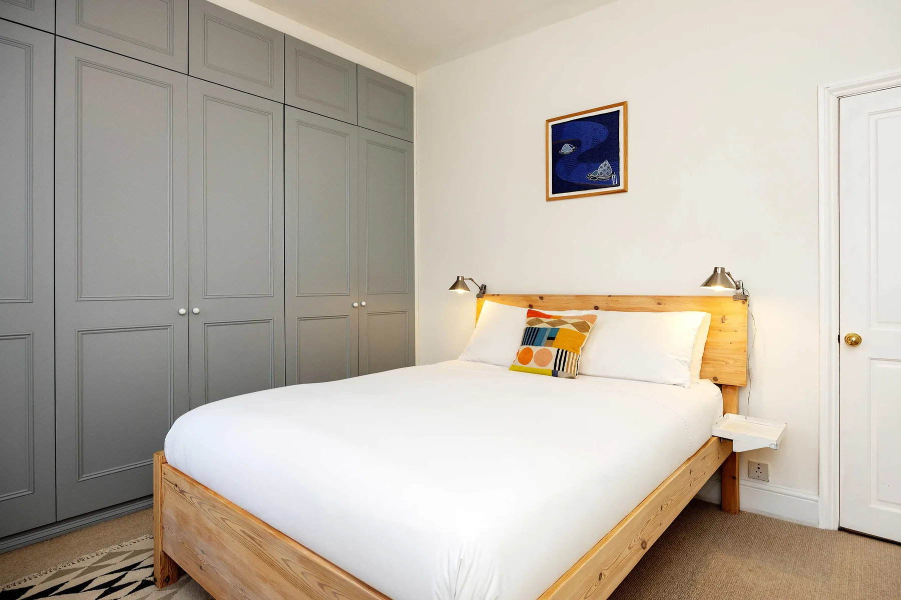 A bedroom with a large bed, built-in cabinets, and a framed picture above the headboard.