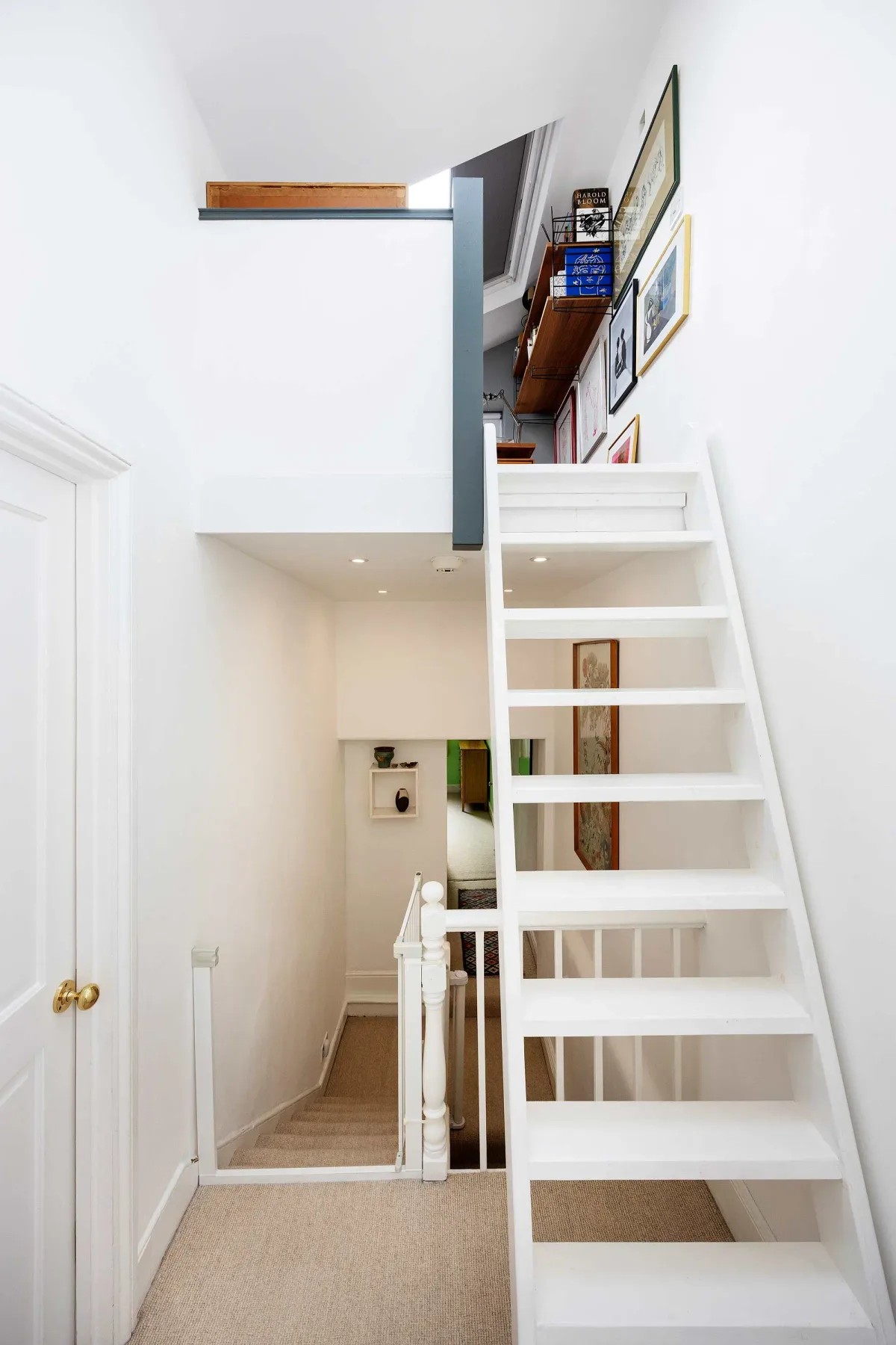 A bright interior hallway with a white staircase leading to a loft.