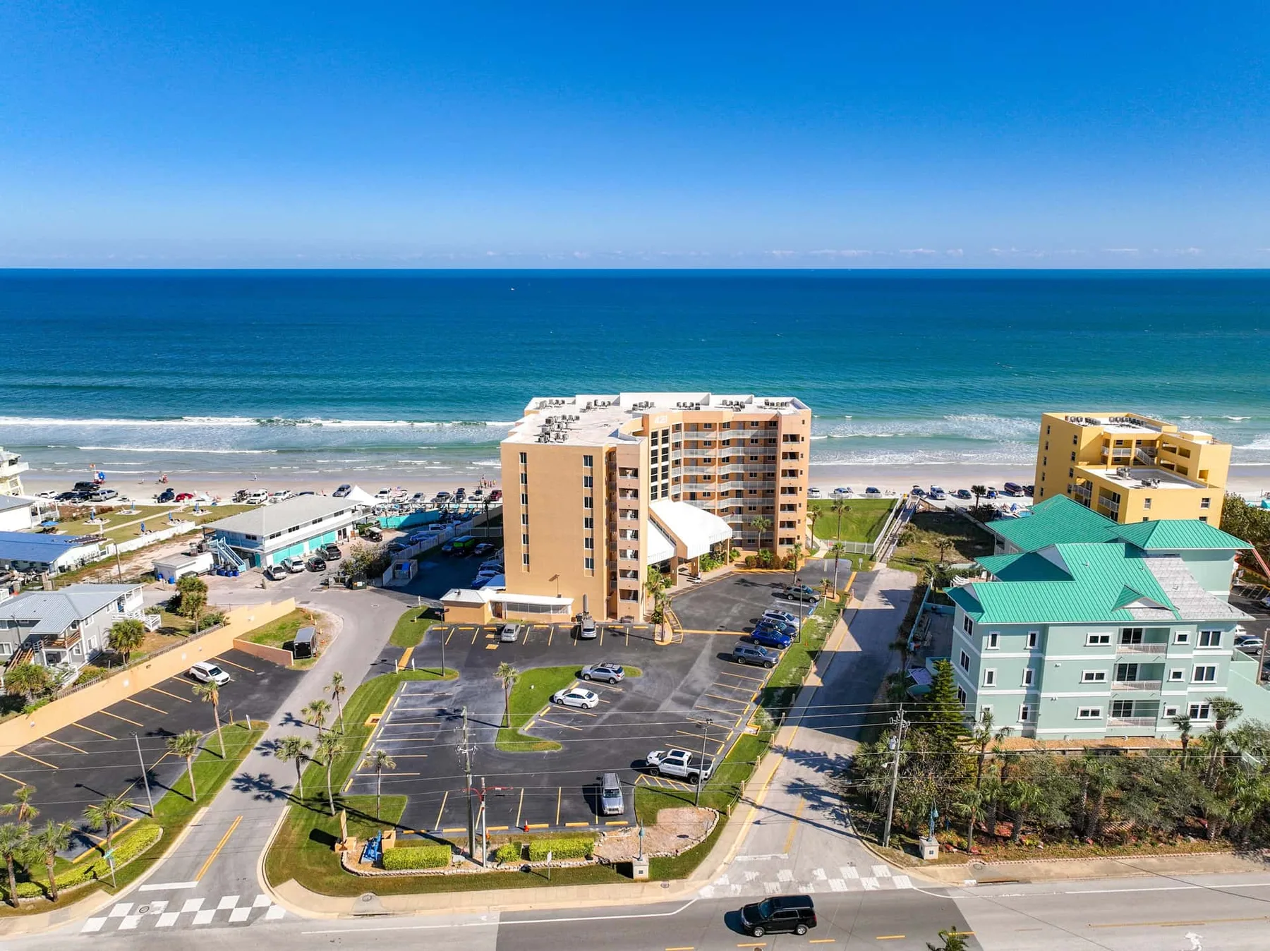 Aerial view of coastal buildings and parking areas beside the ocean.