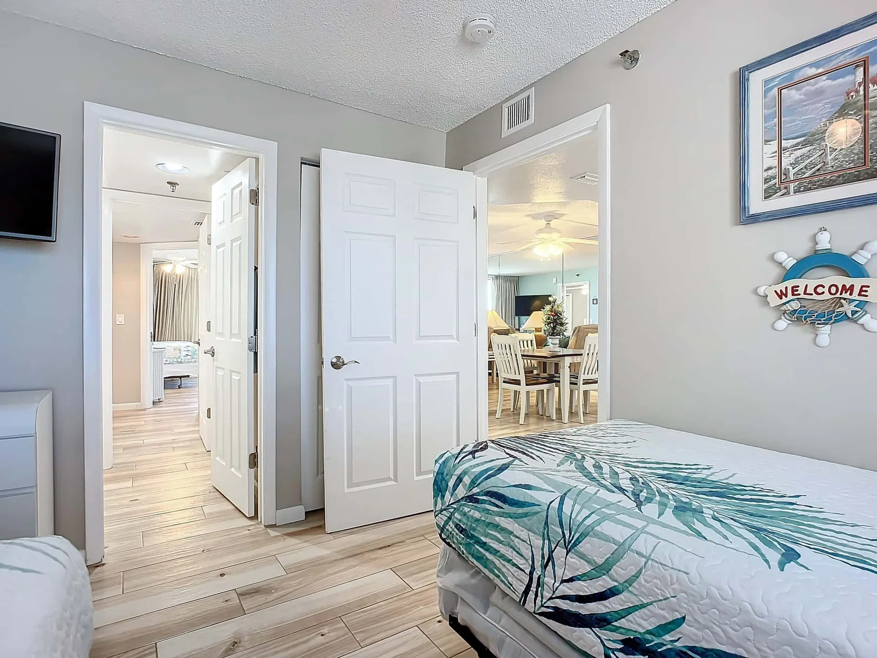 A bedroom with a bed, an open doorway, and a view into a dining area.