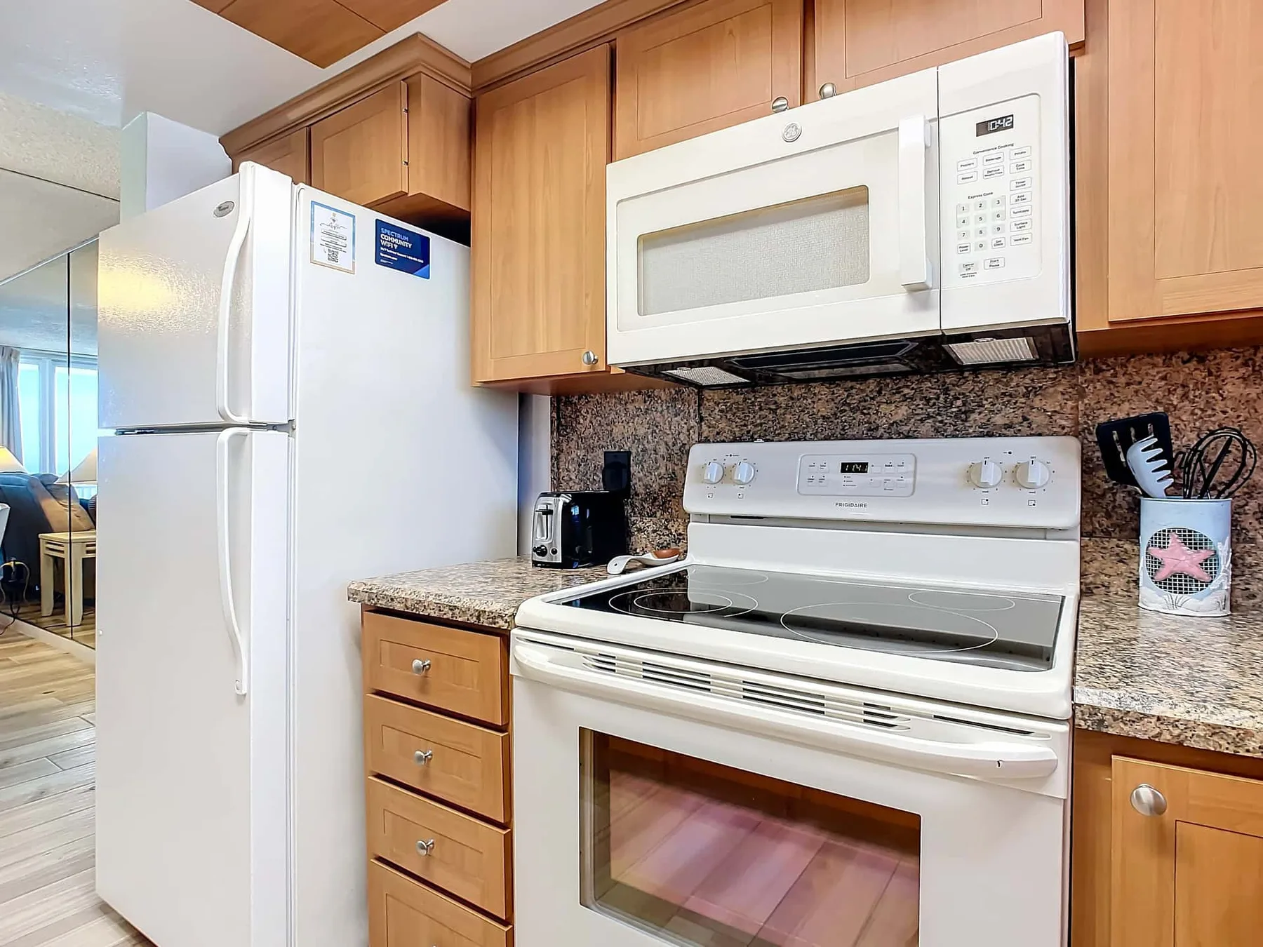A kitchen with a refrigerator, microwave, and stove beneath wooden cabinets.