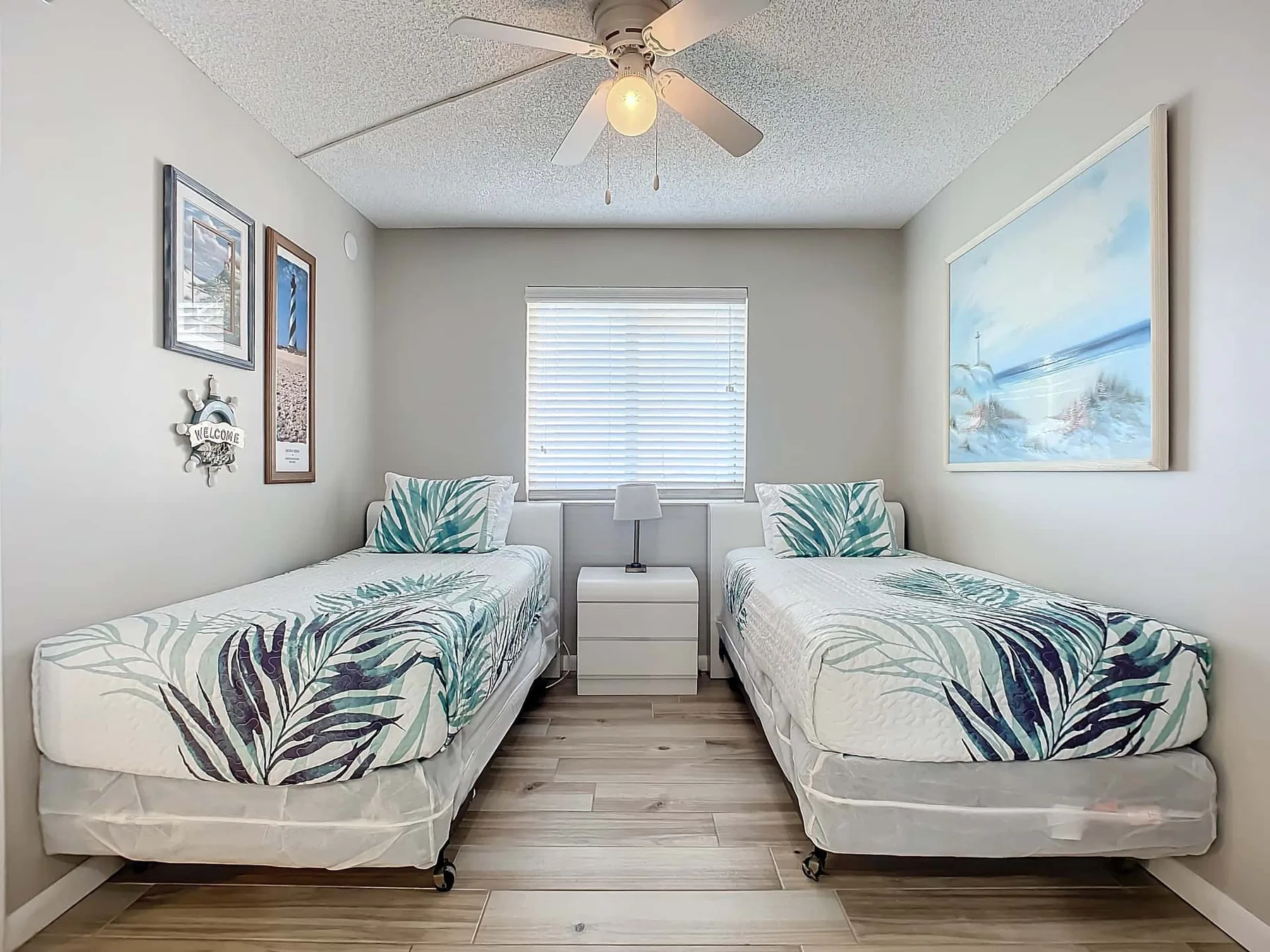 A bedroom with two beds and a window with closed blinds.