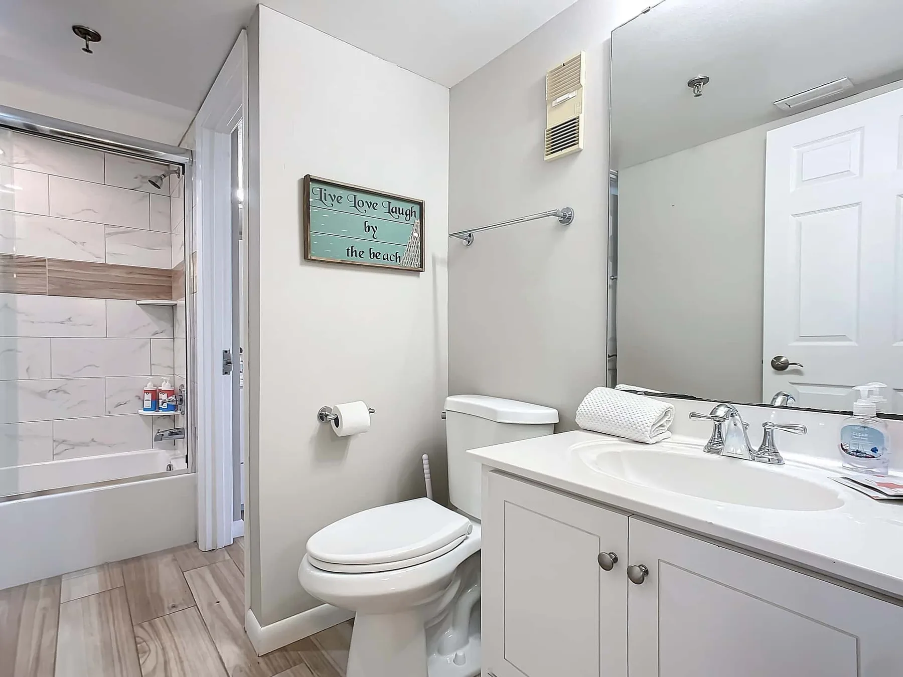 A bathroom with a vanity, toilet, and a tiled shower area.
