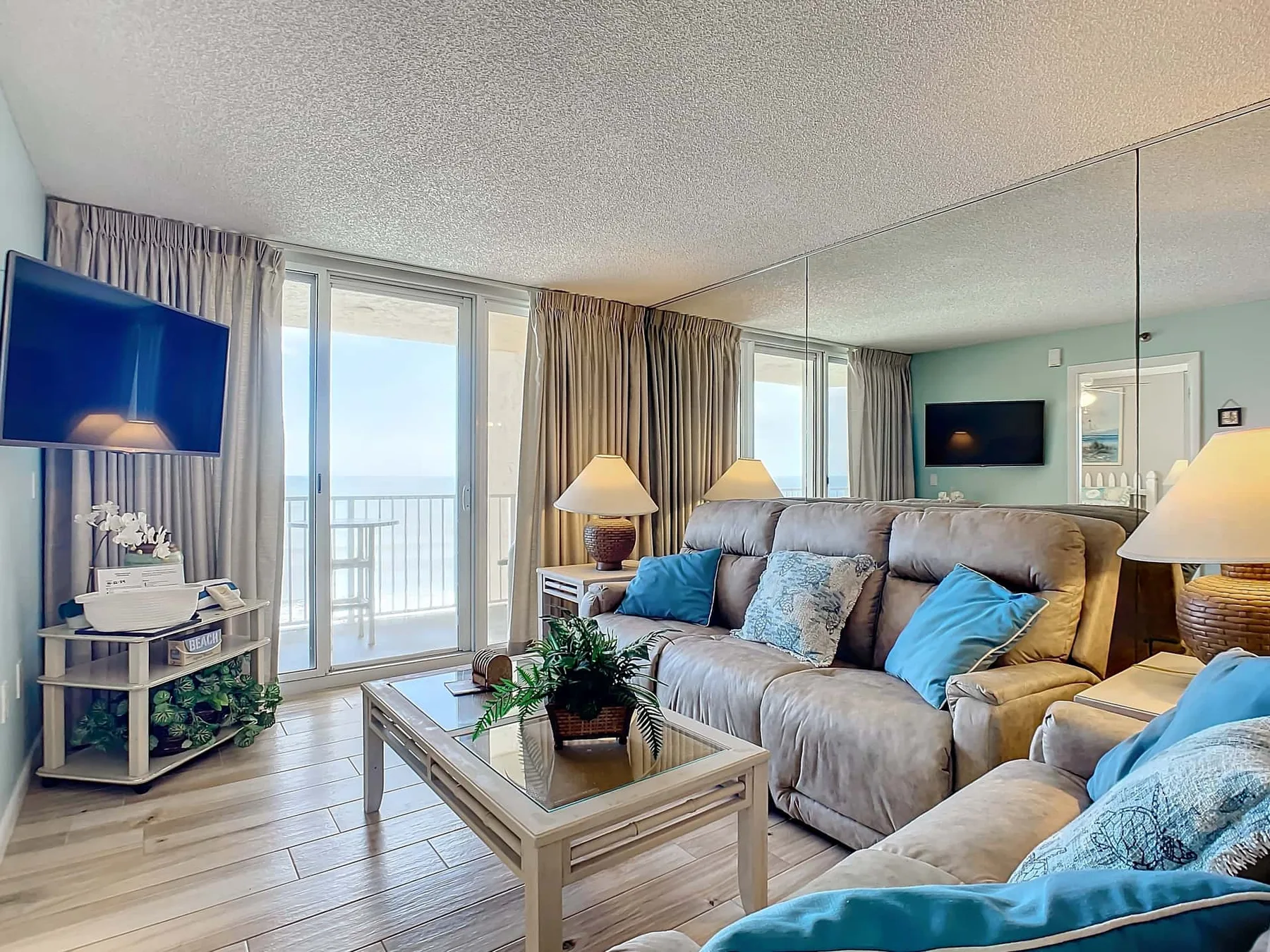 A living room with cushioned seating, a glass coffee table, and a balcony door.