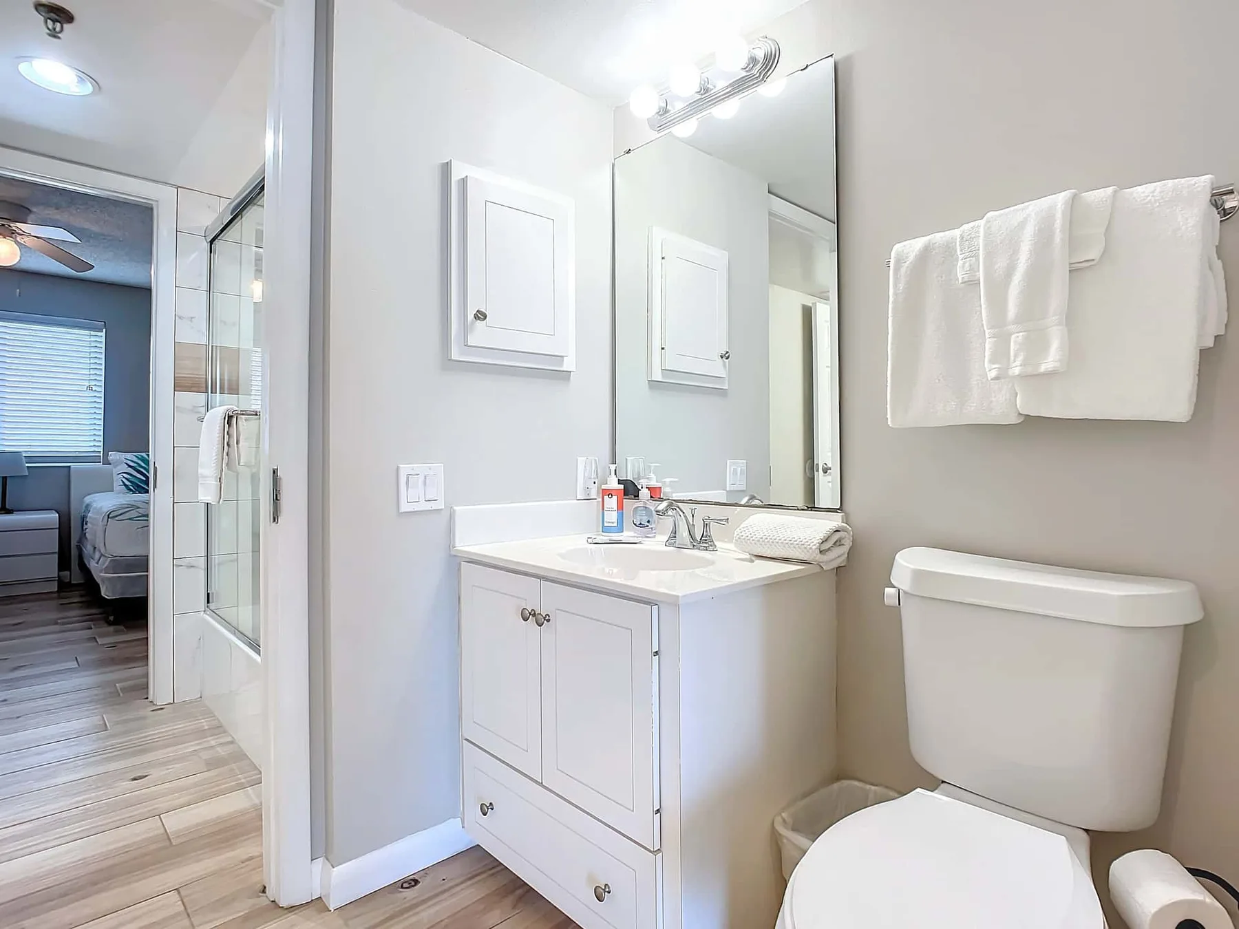 A bright bathroom with a vanity, mirror, and toilet.