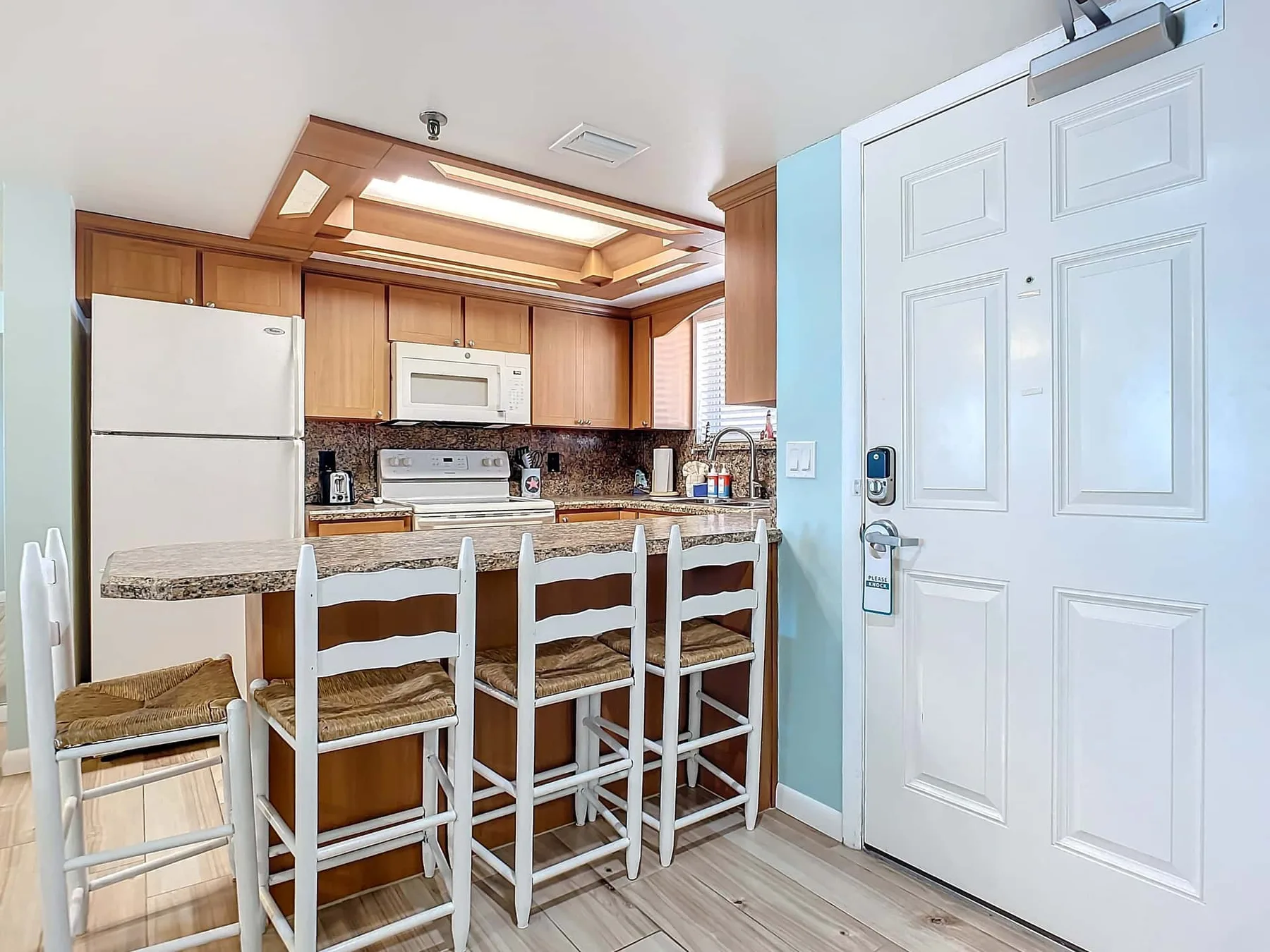 Una cocina con barra para desayunar, taburetes y armarios de madera.