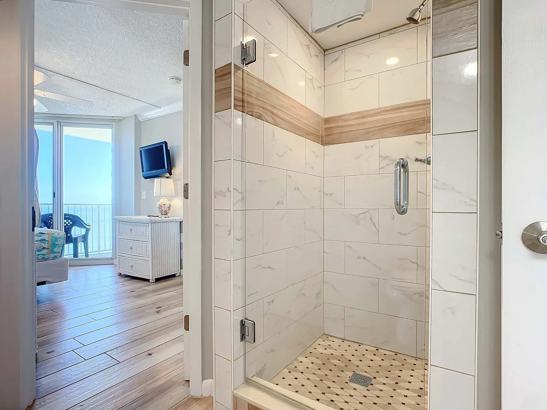 A tiled bathroom shower with a patterned floor is visible beside a bedroom.