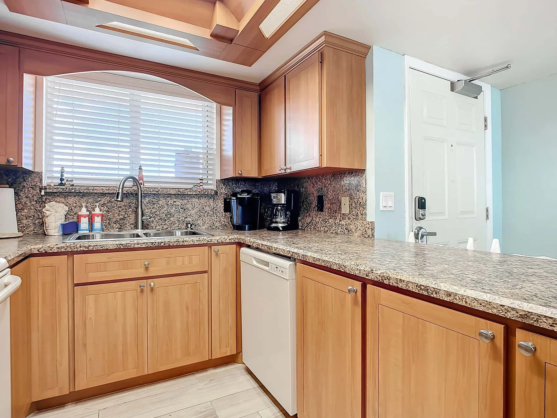 A kitchen with wooden cabinets, stone countertops, and a window over the sink.