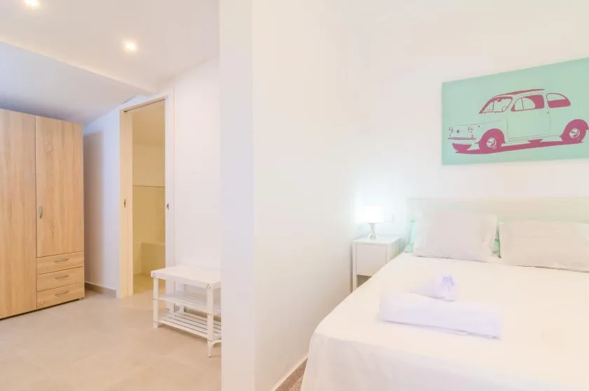Un dormitorio luminoso con una cama doble, una mesita de noche y un armario.