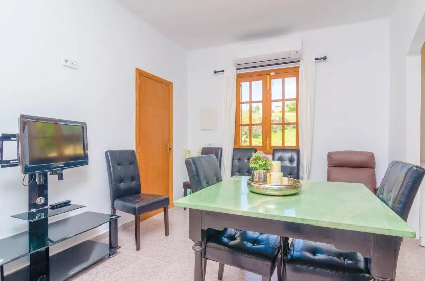 Un comedor con una mesa verde y asientos junto a una ventana.