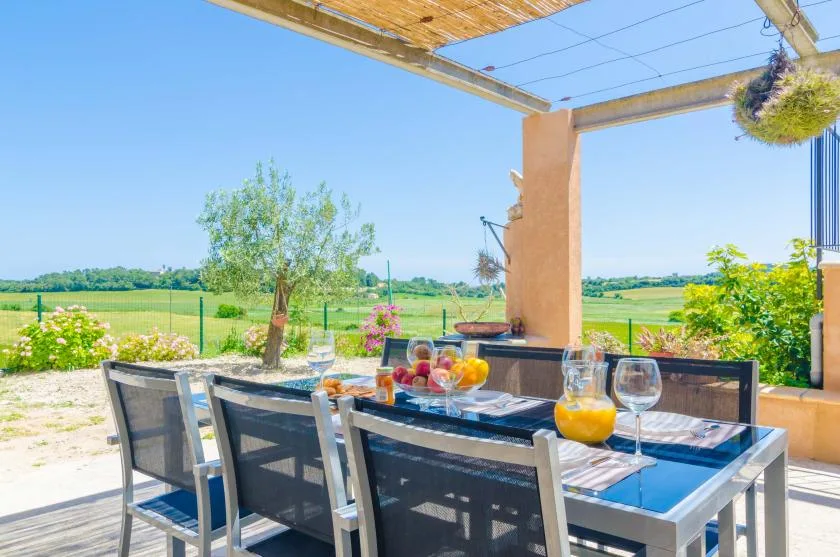 Un comedor al aire libre con mesa y asientos da a campos abiertos.