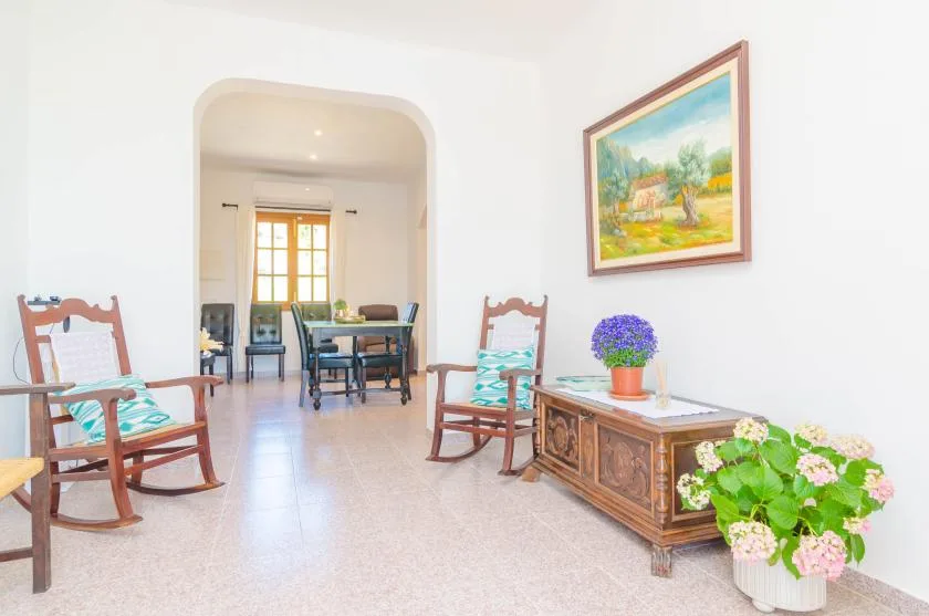 Una sala luminosa con asientos de madera y un mueble bajo bajo un cuadro de paisaje.