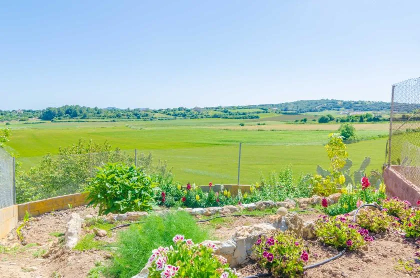 Un jardín de flores mira hacia amplios campos verdes y colinas lejanas.