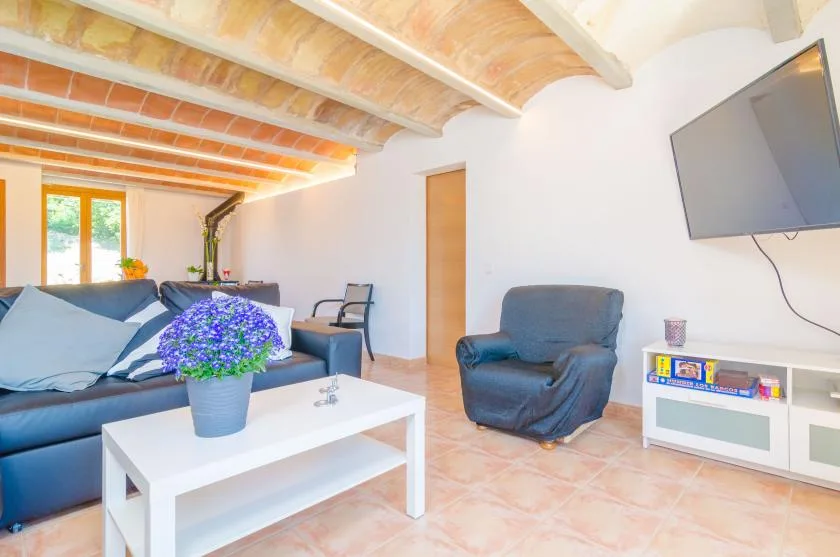 Una sala luminosa con asientos, una mesa de centro blanca y un televisor en la pared.