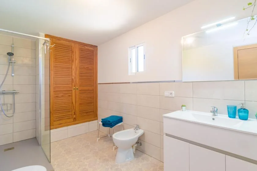 Un baño luminoso con ducha, inodoro y lavabo.