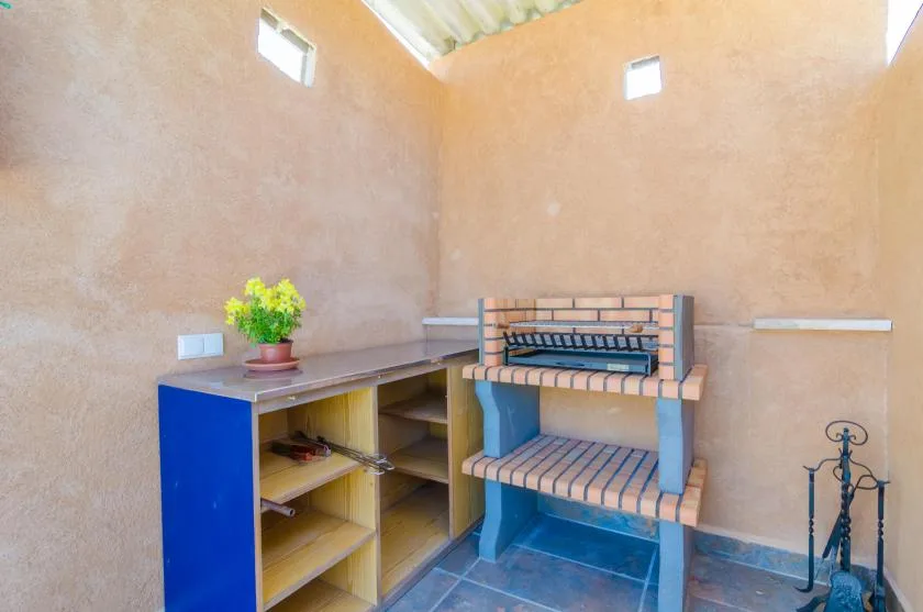 Una pequeña zona de cocina interior tiene estantes empotrados y una barbacoa de ladrillo.