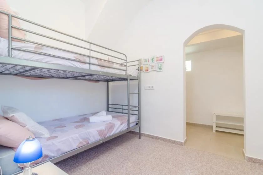 Un dormitorio luminoso con literas y una puerta arqueada.