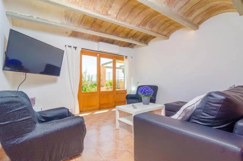 Una sala de estar con asientos oscuros, una mesa de centro y una puerta de madera con vidrio.