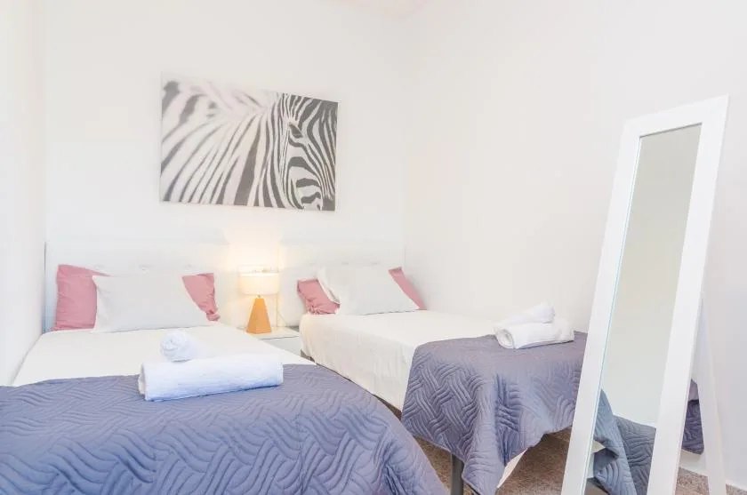 Un dormitorio luminoso con dos camas y un cuadro de estampado de cebra.