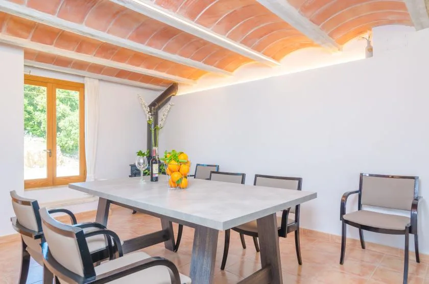 Un comedor luminoso con una mesa larga y sillas junto a una puerta acristalada.