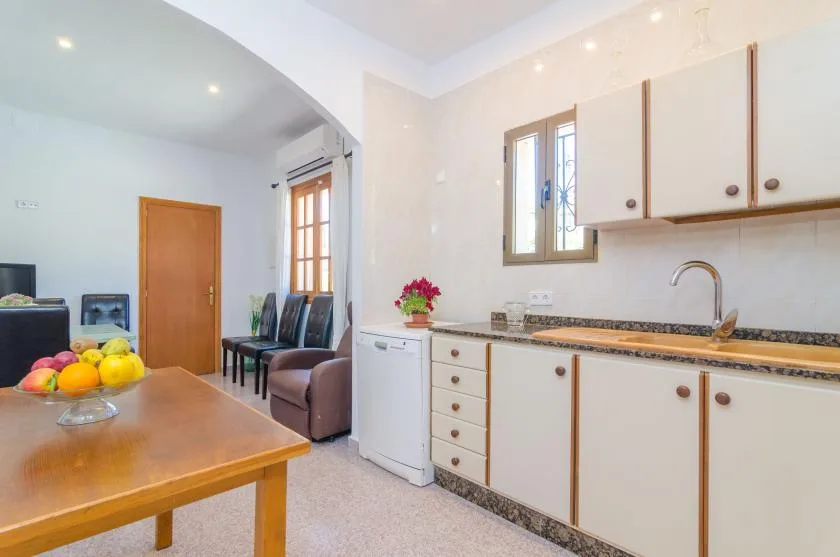 Una cocina luminosa con una mesa de comedor y armarios blancos junto a la pared.