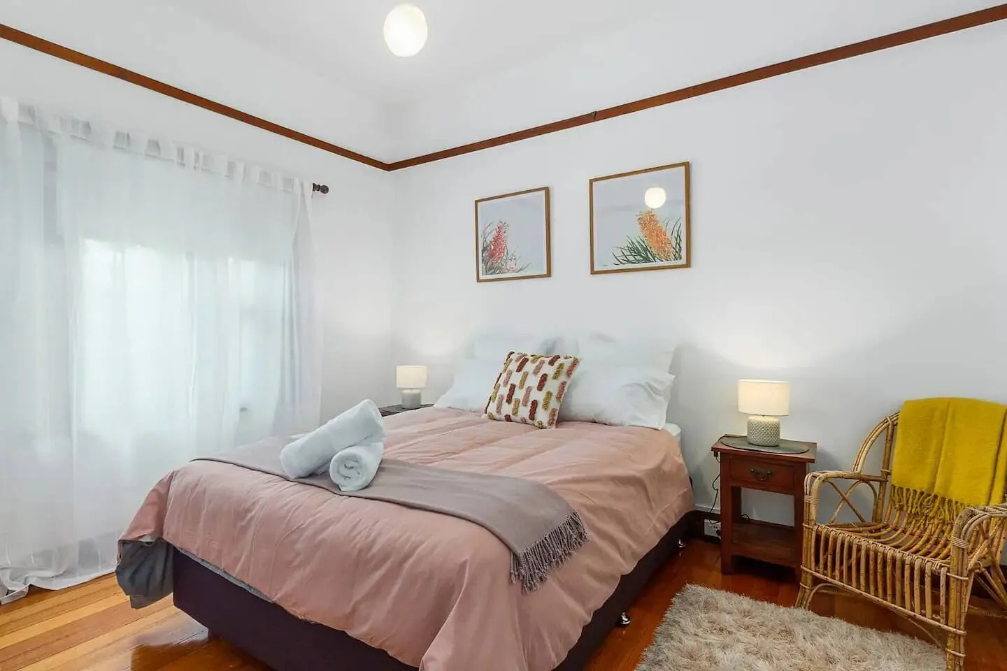 Un dormitorio con una cama tendida y una silla de mimbre al lado.