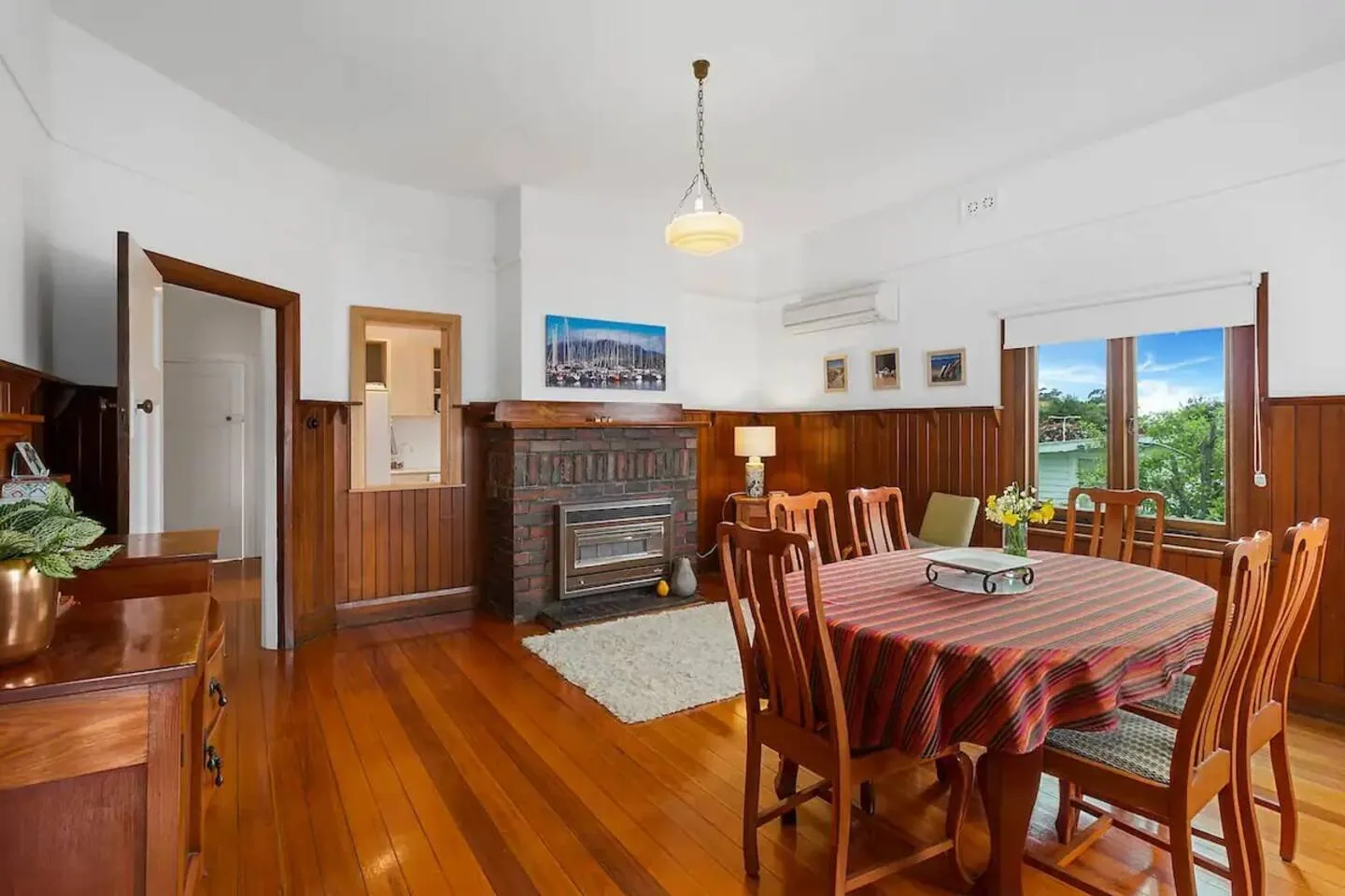 Comedor con una mesa amplia y asientos de madera junto a las ventanas.