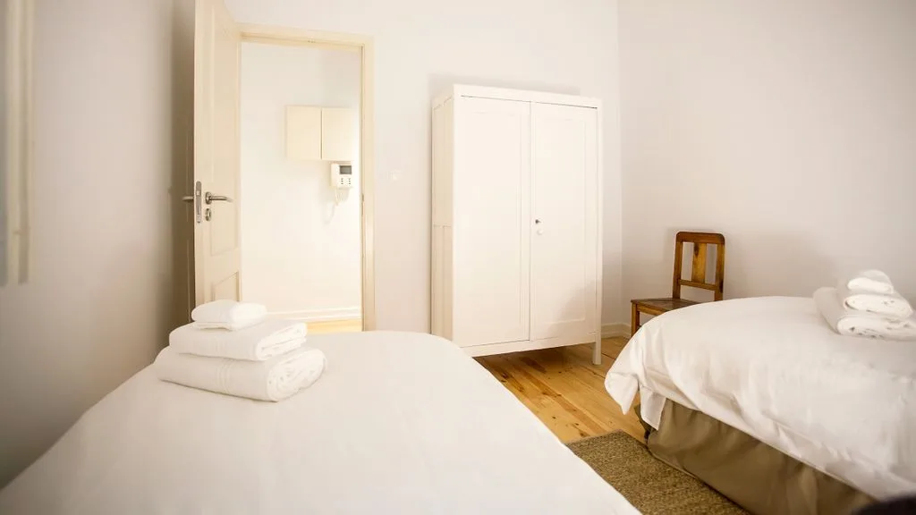 Un dormitorio con dos camas, un armario y toallas dobladas.