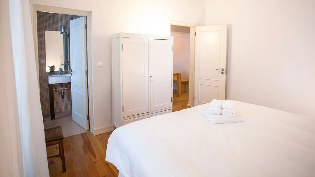 Dormitorio con una cama blanca, armarios y puertas abiertas.